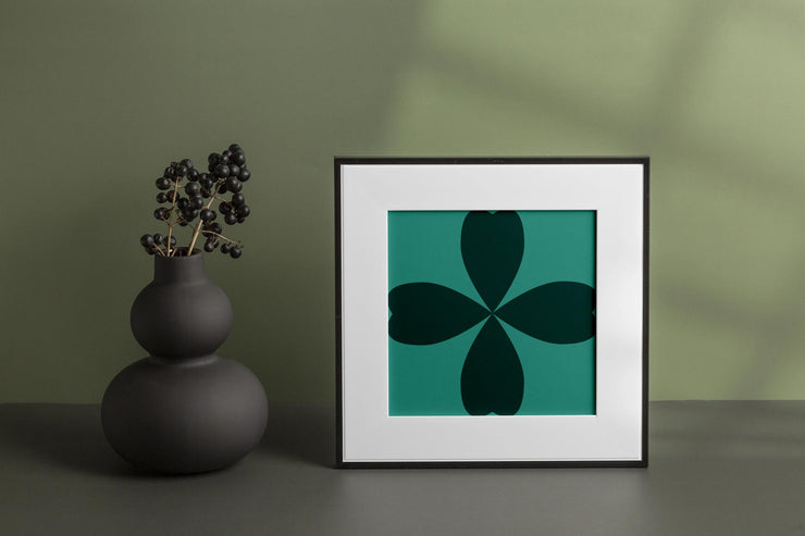 Abstract Cloverleaf Wall Art in a Black Frame on a Green Background with a Decorative Vase